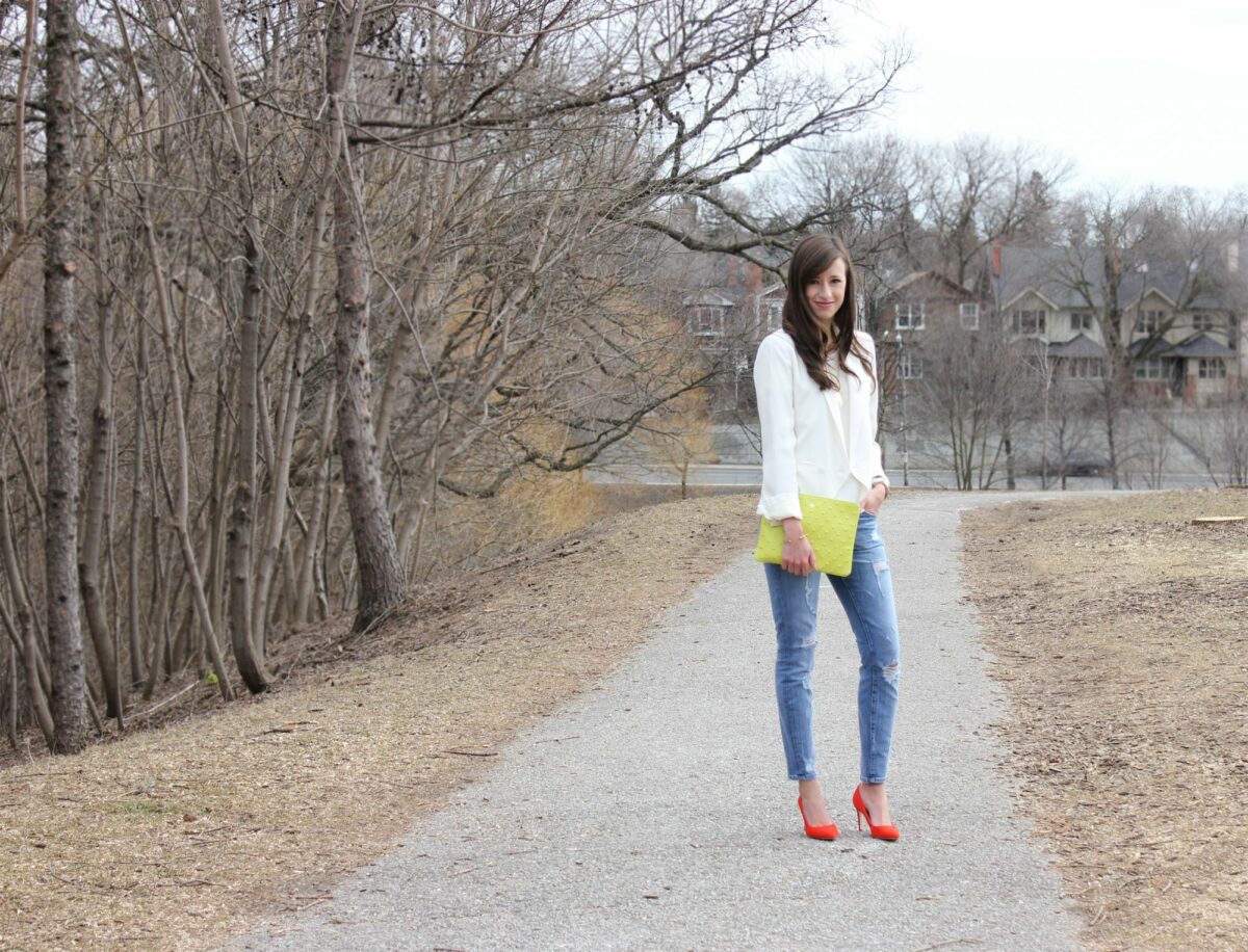 Girl in white top, jeans, red heels and a green bag.